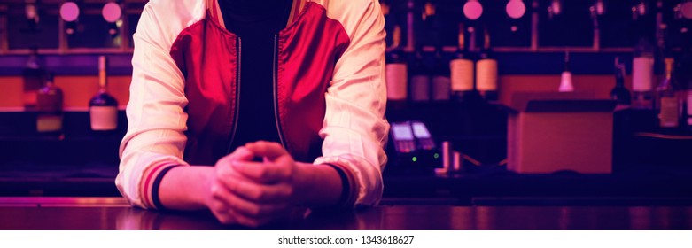Thoughtful Female Bartender Standing At Bar Counter