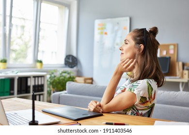 Thoughtful Female Graphic Designer Sitting At Desk Working From Home Office