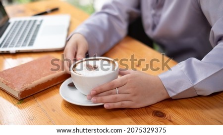 Thoughtful female having coffee while working on laptop at office.