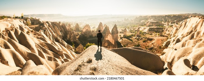 Thoughtful Female Person Stand Look Over Dramatic Valley On Hazy Morning Sunrise With Fairy Chimneys Background. Solo Exploration In Turkey. Cinematic Travel Destination-Cappadocia