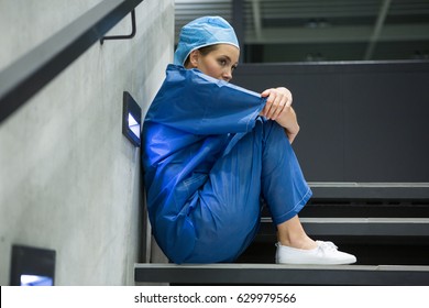 Thoughtful female surgeon sitting on staircase in hospital - Powered by Shutterstock