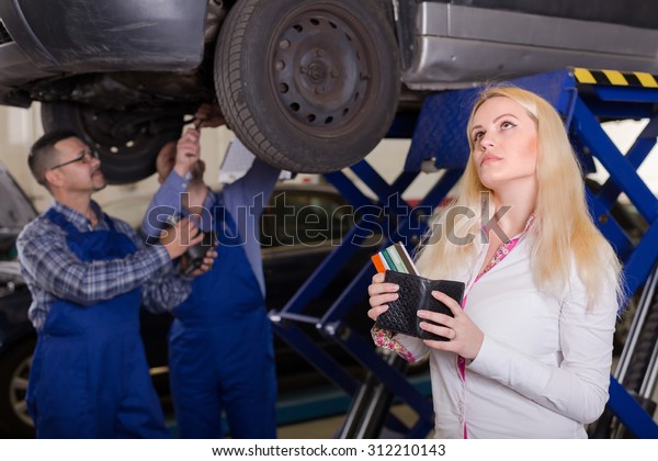 Thoughtful\
girl with credit cards at auto repair shop\

