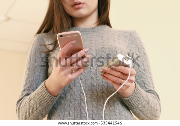 Thoughtful girl plays in the phone and infects it\
by power bank. Power bank in girl\'s hands. Using power bank and\
playing games.