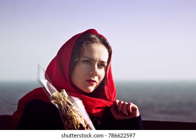 Thoughtful girl in a red shawl with flowers on the background of the sea - Powered by Shutterstock