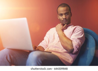 Thoughtful handsome professional IT programmer thinking about new features for implementation in personal startup project and surfing information on internet via modern laptop computer connected to 4G