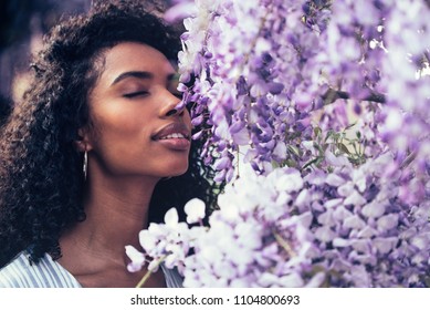 Thoughtful Happy Young Black Woman Surrounded By Flowers