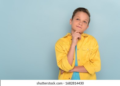 thoughtful kid looking up on blue background with copy space