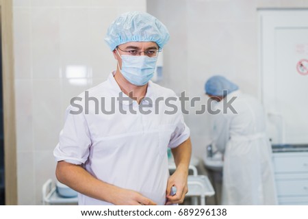 Thoughtful male surgeon wearing surgical mask in hospital