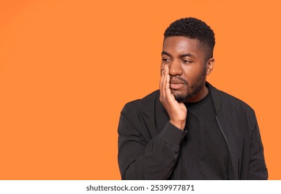 A thoughtful man contemplates in front of a vibrant orange backdrop during a creative studio session - Powered by Shutterstock