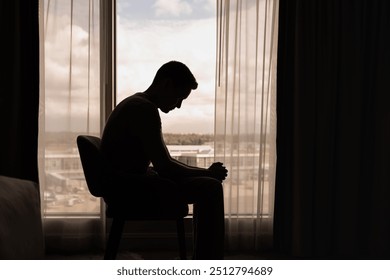 thoughtful man in a dark room with head down, Portrait of thoughtful sad man alone. prayer,  Fear, sadness, abuse, depression, addiction. - Powered by Shutterstock