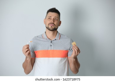Thoughtful man with nicotine patch and cigarette on light grey background