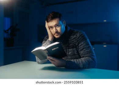 A thoughtful man is seen reading the Bible in his dimly lit home, wearing a sweater, and engaging in a quiet moment of spiritual connection and contemplation. - Powered by Shutterstock