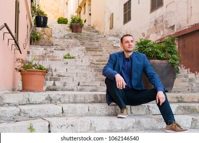 The thoughtful man sits on steps of the narrow street - Powered by Shutterstock