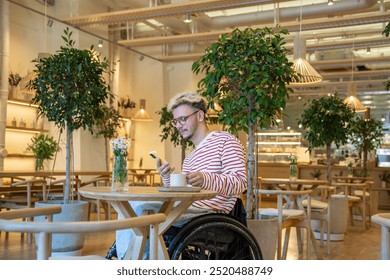 Thoughtful man in wheelchair drinking coffee at cafe table, using smartphone. Guy take break from work, chatting in messenger in phone, typing message, anticipating meeting in coffee shop alone.  - Powered by Shutterstock