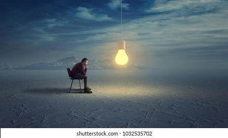 Thoughtful man in wilderness looks to a yellow light bulb coming down from the sky.