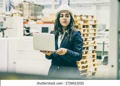 Thoughtful Manager Holding Laptop At Printing Factory. Focused Asian Employee Holding Open Laptop At Manufacturing Plant. Print Manufacturing Concept