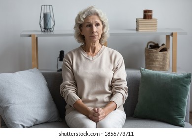 Thoughtful mature senior woman lost in thoughts, sitting with folded hands on couch alone, upset frustrated middle aged female looking in distance, thinking about past, feeling lonely and depressed - Powered by Shutterstock