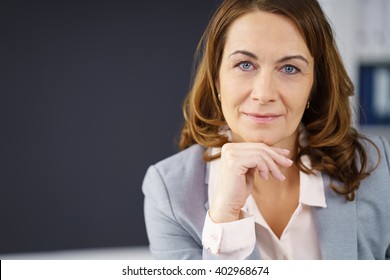 Thoughtful middle-aged businesswoman resting her chin on her hand and looking straight into the camera, close up head and shoulders portrait with copy space - Powered by Shutterstock