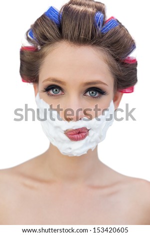 Thoughtful model in hair curlers posing with shaving foam on white background