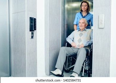 Thoughtful nurse pushing senior patient in wheelchair at hospital lift