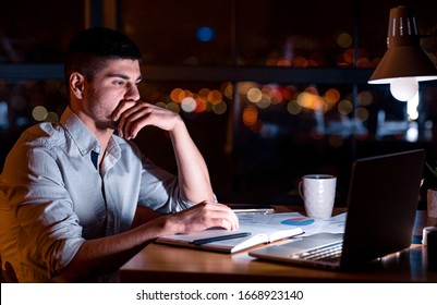 Thoughtful Office Manager At Laptop Working On Business Report Late At Night Sitting At Workpalce Indoors. Low Light - Shutterstock ID 1668923140