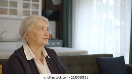 The thoughtful old woman was at home alone in thought. Loneliness grief concept. A woman alone at home feels uneasy when she looks at the empty advertising space on the right of the screen. - Shutterstock ID 2255080951