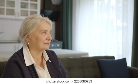 The thoughtful old woman was at home alone in thought. Loneliness grief concept. A woman alone at home feels uneasy when she looks at the empty advertising space on the right of the screen. - Shutterstock ID 2255080953
