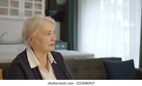 The thoughtful old woman was at home alone in thought. Loneliness grief concept. A woman alone at home feels uneasy when she looks at the empty advertising space on the right of the screen. - Shutterstock ID 2255080957