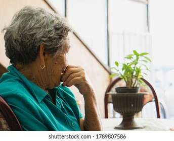 Thoughtful Older Woman Sitting On A Chair