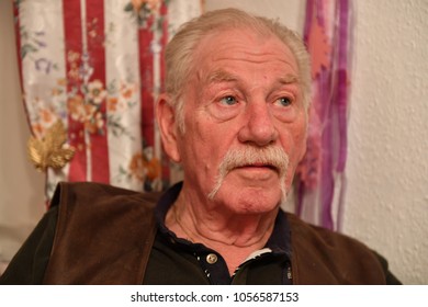 A Thoughtful Pensioner With A 
Walrus Mustache In His Living Room.