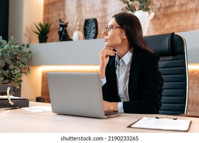 Thoughtful pensive caucasian successful clever businesswoman with glasses, company financial manager, ceo, sits at a desk in the office, looks away, thinks about a project, plans a business plan