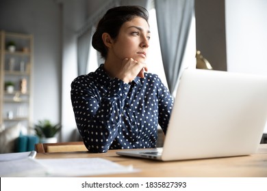 Thoughtful pensive Indian unmotivated employee sit at workplace desk distracted from computer work ponder look out the window feel tired after long workday. Business vision, lack of motivation concept - Powered by Shutterstock