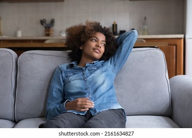 Thoughtful Positive Black Teen Girl Relaxing On Comfortable Sofa In Living Room, Taking Deep Breath Of Fresh Air, Enjoying Break, Leisure Time At Home, Looking Away, Thinking, Dreaming