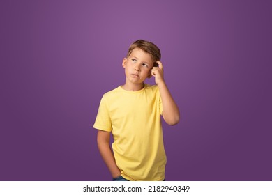 Thoughtful preteen kid boy standing with puzzled serious expression, making choise thinking against purple background. Studio shot