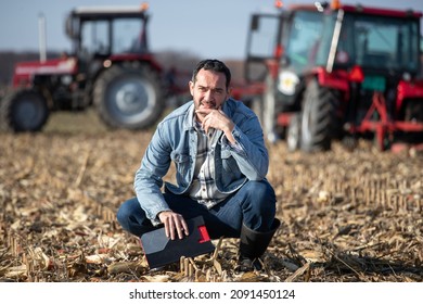 Thoughtful rancher brainstorming while crouching at agricultural field.