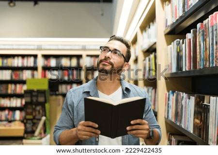 Thoughtful reflexive man thinking and using his imagination while reading a novel at the book shop