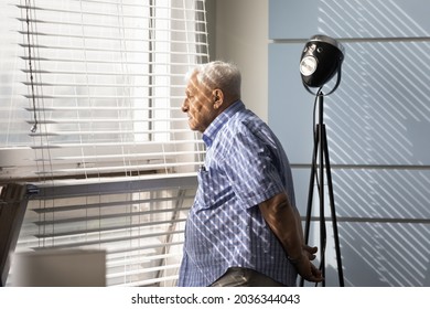 Thoughtful Sad Senior 80s Man Looking Out Of Window, Thinking Over Memory Loss, Dementia, Alzheimer Disease, Feeling Lonely, Depressed, Upset. Old Age Problems, Elderly Healthcare Concept