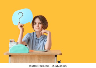 Thoughtful schoolboy with stationery and speech bubble sitting on desk against yellow background - Powered by Shutterstock