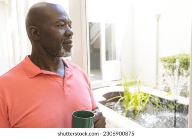 Thoughtful senior african american man having coffee looking out of window at home, copy space. Senior lifestyle, retirement and domestic life, unaltered. - Powered by Shutterstock