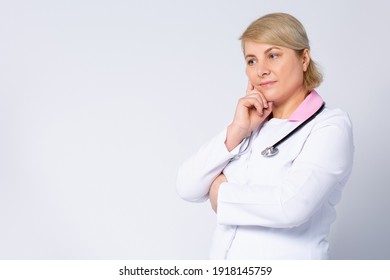 Thoughtful Senior Female Doctor, Lost In Thoughts. Worried Old Physician Thinking Of Healthcare Question, Concerned Of Challenge, Feels Anxious, Difficult Decision. Side Space. High Quality Photo