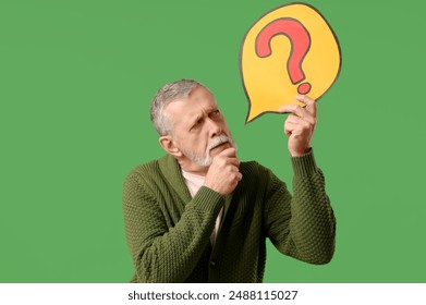 Thoughtful senior man holding speech bubble with question mark on green background - Powered by Shutterstock