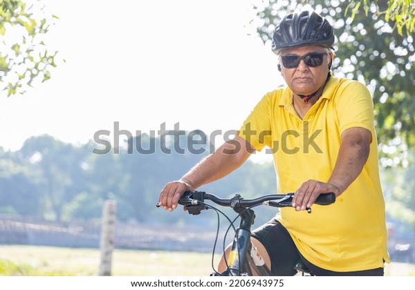 Thoughtful senior man in protective sportswear\
leaning on bicycle handlebar\
outdoors