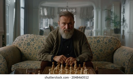 Thoughtful senior man thinking game strategy in classic interior. Single elderly chess player look chess board in luxury room. Focused mature model gentleman playing chess alone at home. Wisdom hobby  - Powered by Shutterstock