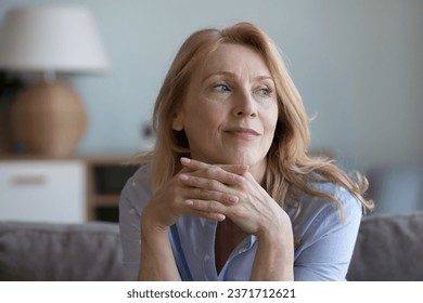 Thoughtful senior mature 60s blonde woman sitting on home couch, leaning chin on hands, looking away with good thoughts, thinking over future retirement plans, enjoying leisure time - Powered by Shutterstock