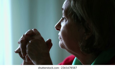 Thoughtful senior woman gazing at window in mental reflection. Pensive elderly lady in contemplation - Powered by Shutterstock