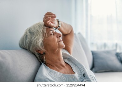 Thoughtful senior woman relaxing on bed. Senior woman relaxing at home. Woman having a nap on the sofa relaxing with her head tilted back on the cushion and eyes closed - Powered by Shutterstock