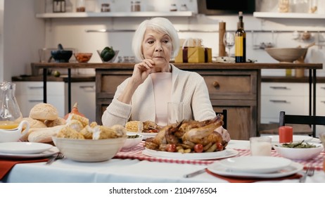 Thoughtful Senior Woman Sitting Alone At Table Served With Thanksgiving Dinner In Kitchen