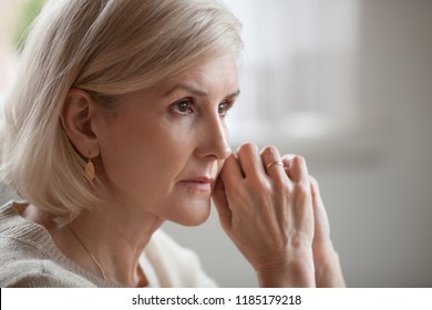 Thoughtful serious anxious mature senior woman feeling blue worried about problems, pensive upset sad middle aged grey haired lady looking away thinking of loneliness, getting older and depression - Shutterstock ID 1185179218