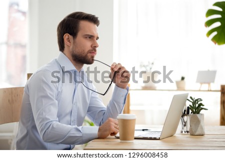 Thoughtful serious businessman lost in thoughts at work with laptop, focused executive thinking of problem solution, worried puzzled manager pondering question or solving business issues at workplace