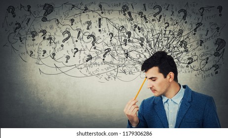 Thoughtful stressed young man with a mess in his head closed eyes pointing pencil to forehead. Anxiety and headache feeling.